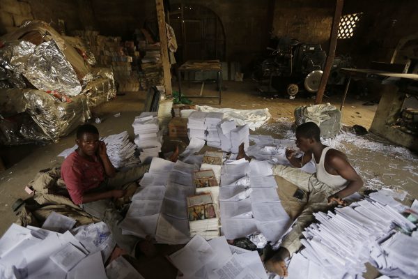 In this photo taken Sunday April, 3. 2016, young men sort out newly printed books in Kano, Nigeria. In the local market stalls are signs of a feminist revolution with piles of poorly printed books by women, as part of a flourishing literary movement centered in the ancient city of Kano, that advocate against conservative Muslim traditions such as child marriage and quick divorces. dozens of young women are rebelling through romance novels, many hand-written in the Hausa language, and the romances now run into thousands of titles. (AP Photo/Sunday Alamba)