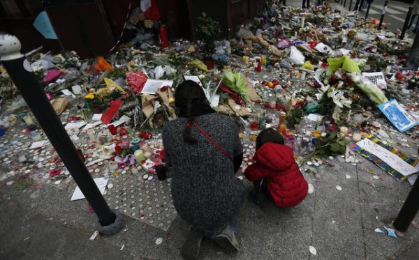 Një grua dhe një fëmijë vënë lule përpara restorantit ku u krye një nga sulmet në Francë(AP Photo/Frank Augstein)