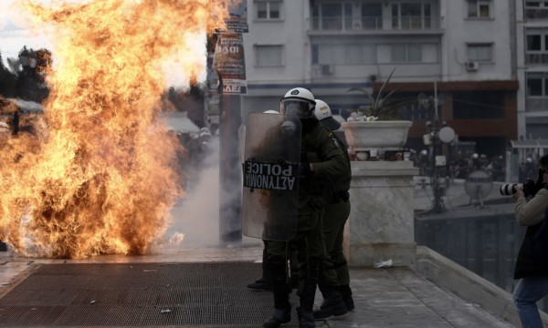 Policët grekë po qëndrojnë mes tymit gjatë përleshjeve me protestuesit më 4 shkurt 2016 në Athinë. (AP Photo/Petros Giannakouris)