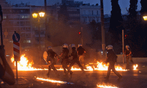 Oficerë të policisë greke vrapojnë ndërkohë që protestuesit hedhin bomba me naftë gjatë përleshjeve në Athinë më 15 korrik 2015. (AP Photo/Emilio Morenatti)