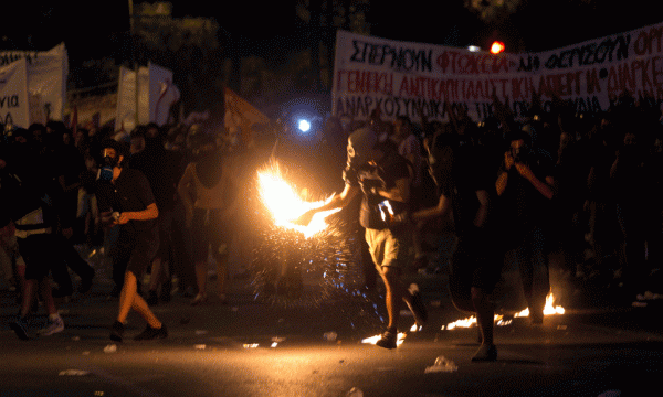 Protestuesit hedhin shishe me naftë ndaj policisë në përleshjet në Athinë mbrëmjen e 15 korrikut 2015. Protesta po zhvillohet ndërkohë që kryeministri Alexis Tsipras është duke luftuar për të ruajtur unitetin brenda rradhëve të partisë së vet. (AP Photo/Emilio Morenatti)